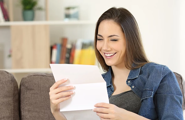 Woman opening mail on couch